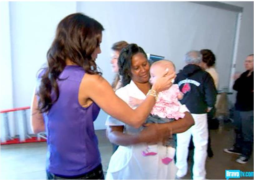 Black baby nurse Gina, holds baby Bryn as Mother Bethenny strokes Bryn's hair.