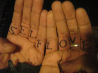 Tattoo on inside of someone's fingers that says "self love"
