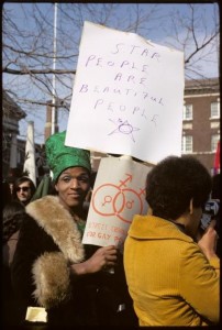 Marsha P Johnson holding a sign that reads "STAR PEOPLE ARE BEAUTIFUL PEOPLE"