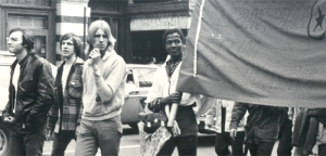 Marsha P Johnson holds part of a banner in a street action.